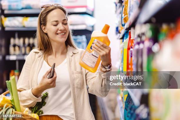 lächelnde frau im supermarkt auf der suche nach einem hygieneprodukt - reinigungsmittel stock-fotos und bilder