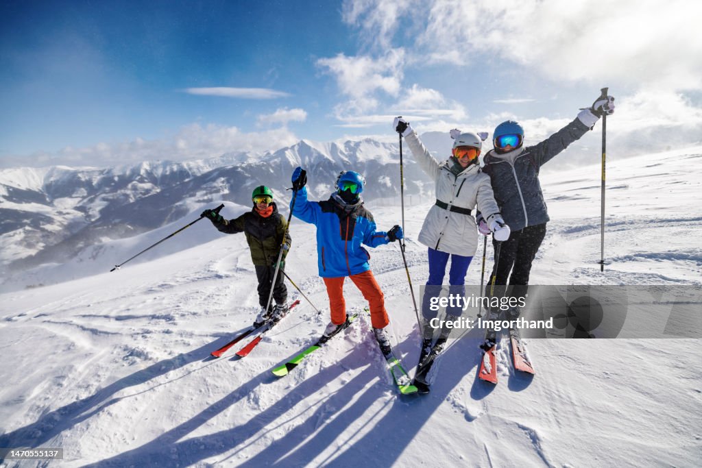 Family enjoy a skiing together in mountains on a sunny winter day