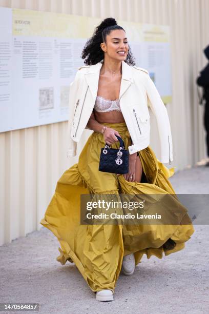 Jessica Aidi wears a white bra, yellow maxi skirt, cream leather jacket and black Dior bag, outside Dior, during Paris Fashion Week - Womenswear Fall...