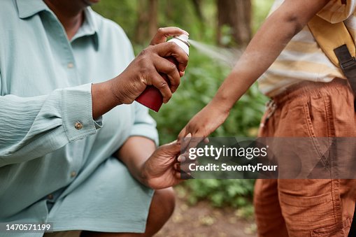 Closeup of caring black mother using baby safe bug repellent for daughter Closeup of caring black mother using baby safe bug repellent for daughter