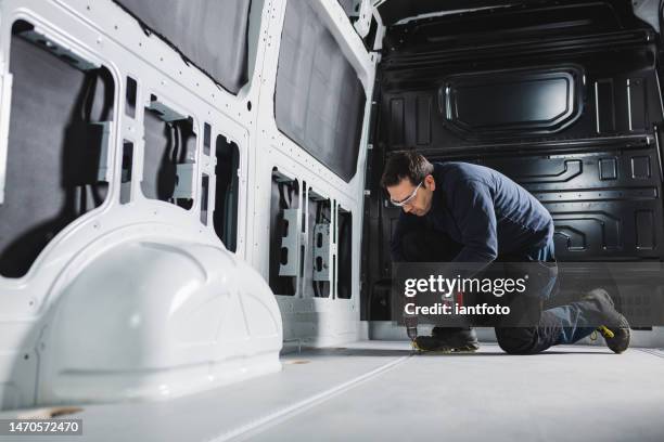 umbau eines transporters zum haus auf rädern. mann bei der arbeit mit einer batteriebetriebenen bohrmaschine in einem lieferwagen. - lieferwagen stock-fotos und bilder