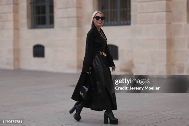 Corina Mihaila Larpin seen wearing long black Schiaparelli coat , gold Schiaparelli belt with pendants and gold long Schiaparelli necklace, gold...