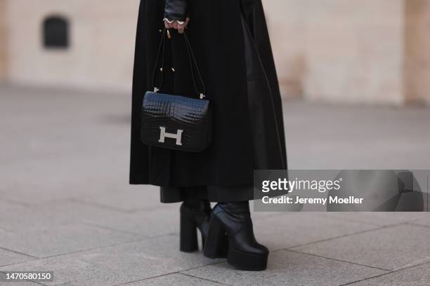 Corina Mihaila Larpin seen wearing long black Schiaparelli coat , gold Schiaparelli belt with pendants, black Yves Saint Laurent plateau boots, long...