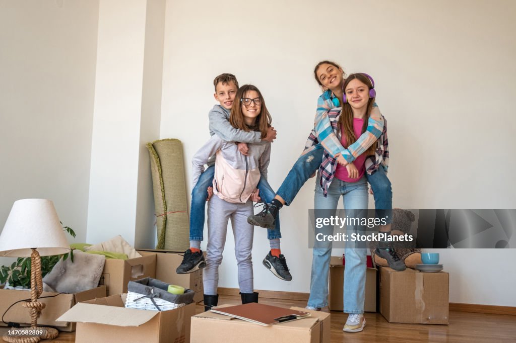 Teenagers have fun moving into a new apartment and pose for a picture.