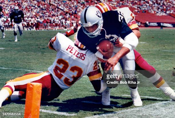 Los Angeles Raiders RB Marcus Allen is stopped short of the goal line by Washington Redskins Tony Peters and Rich Milot during game action August 18,...