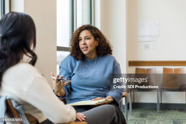 female therapist gestures while talking with the unrecognizeable woman - mental health professional stock pictures, royalty-free photos & images