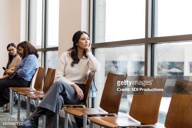 worried young woman sits in the waiting room at the doctor's office - outpatient care stock pictures, royalty-free photos & images