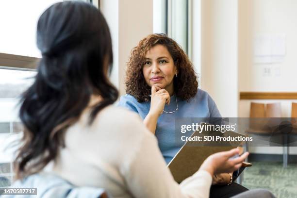 female therapist listens intently to the unrecognizeable woman - vulnerability management stock pictures, royalty-free photos & images