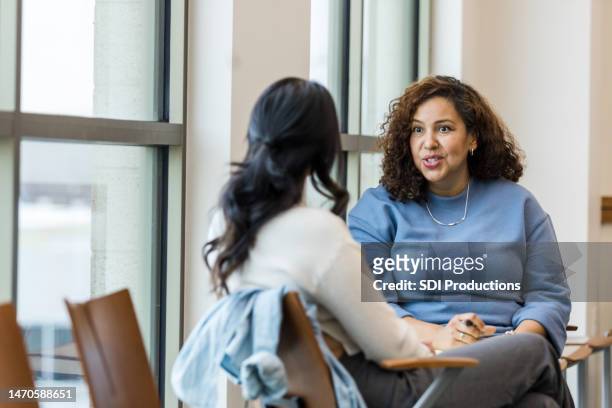 supervisor meets with mid adult female employee to mentor her regarding a new position she is interested in - meeting community stockfoto's en -beelden