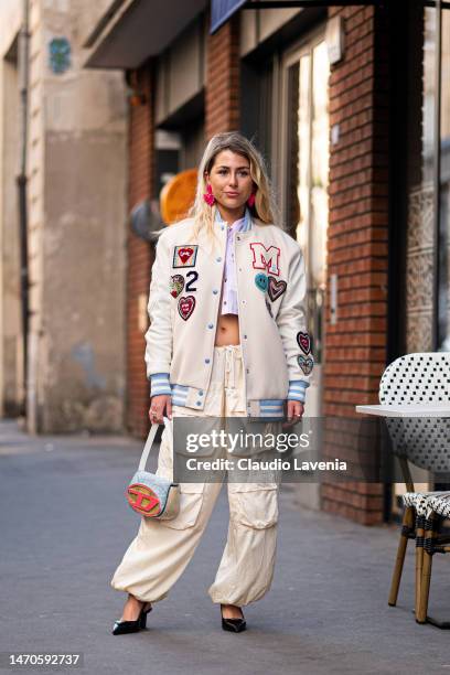 Emma Bonneaud wears a cream decorated bomber jacket, parachute cream pants, pink striped cropped shirt and Diesel bag, outside Victoria/Tomas, during...