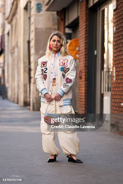 Emma Bonneaud wears a cream decorated bomber jacket, parachute cream pants, pink striped cropped shirt and Diesel bag, outside Victoria/Tomas, during...