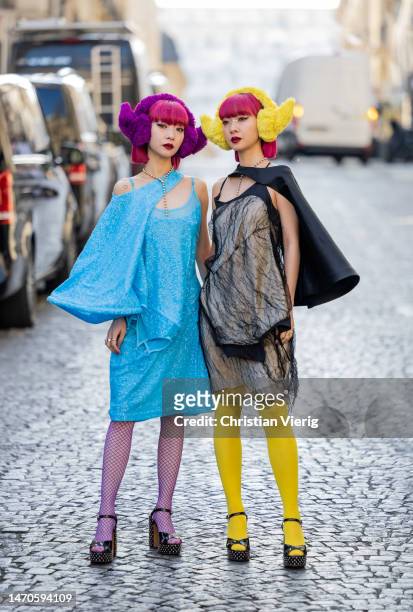 Twins Ami Amiaya wears blue dress, net tights and Aya Amiaya wears black dress, yellow tights, ear warmers outside Undercover during Paris Fashion...
