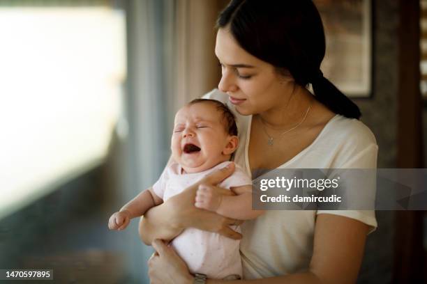 mother taking car of a crying newborn baby - crying stock pictures, royalty-free photos & images