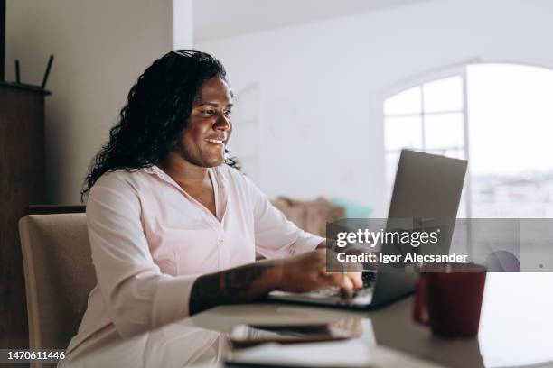 donna transgender che lavora sul computer portatile a casa - transgender foto e immagini stock
