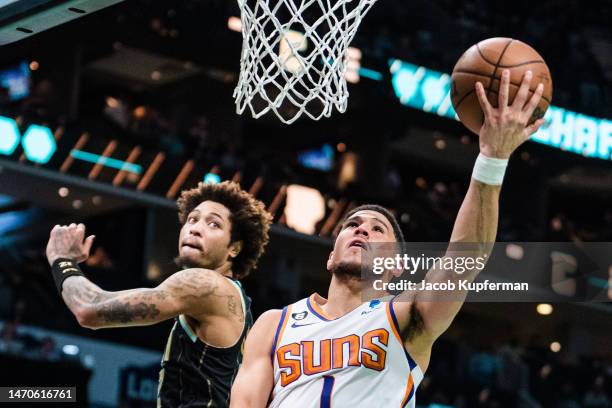 Devin Booker of the Phoenix Suns drives to the basket while guarded by Kelly Oubre Jr. #12 of the Charlotte Hornets in the second quarter during...