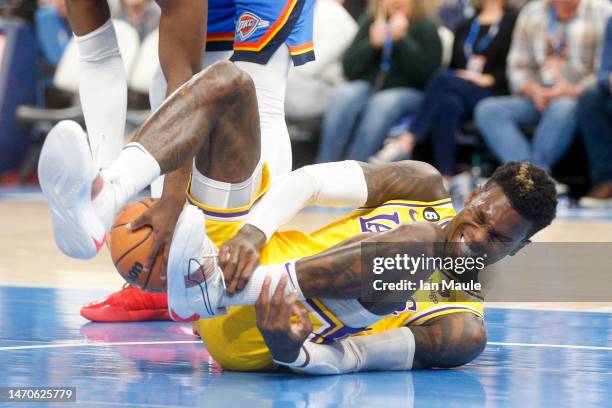 Dennis Schroder of the Los Angeles Lakers grabs his ankle after driving to the basket during the first quarter against the Oklahoma City Thunder at...