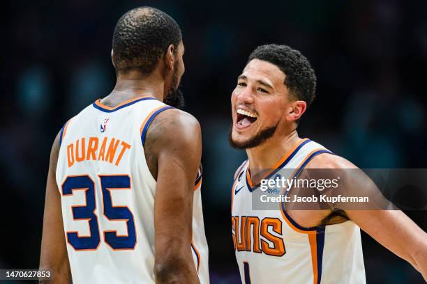 Kevin Durant celebrates with Devin Booker of the Phoenix Suns in the fourth quarter during their game against the Charlotte Hornets at Spectrum...