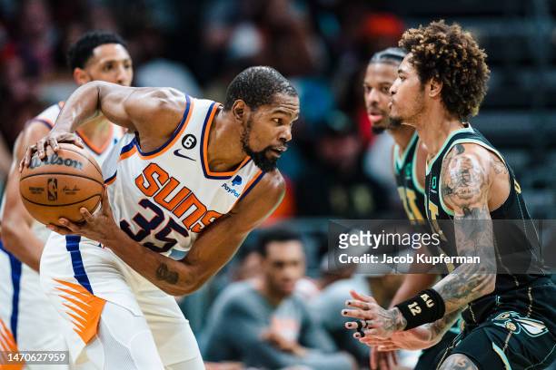 Kelly Oubre Jr. #12 of the Charlotte Hornets guards Kevin Durant of the Phoenix Suns in the fourth quarter during their game at Spectrum Center on...