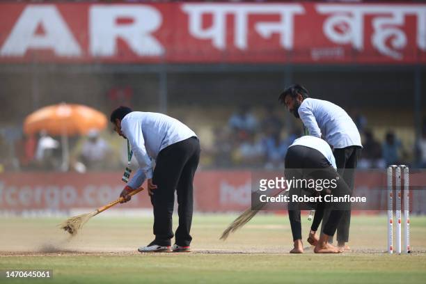 The pitch is swept at the drinks break during day two of the Third Test match in the series between India and Australia at Holkare Cricket Stadium on...
