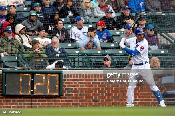 Trey Mancini of the Chicago Cubs warms up in front of the pitch clock during the fourth inning of a spring training game against the Seattle Mariners...