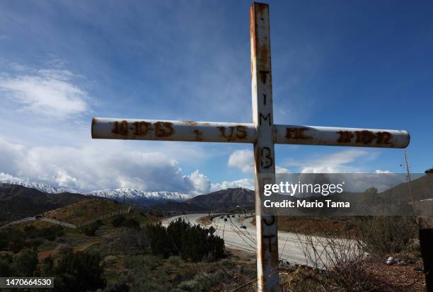 Cross stands with snow-covered mountains in the distance in Los Angeles County on March 01, 2023 near Acton, California. The final in a series of...