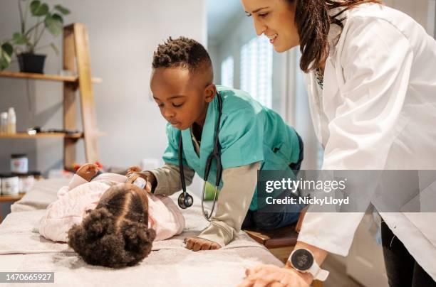 little boy taking his sister's temperature in his mom's doctor's office - role play stockfoto's en -beelden