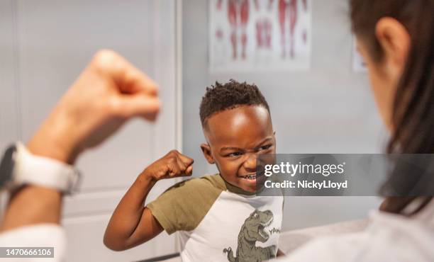 niño sonriente flexionándose después de una cita con un médico - flexionar los músculos fotografías e imágenes de stock