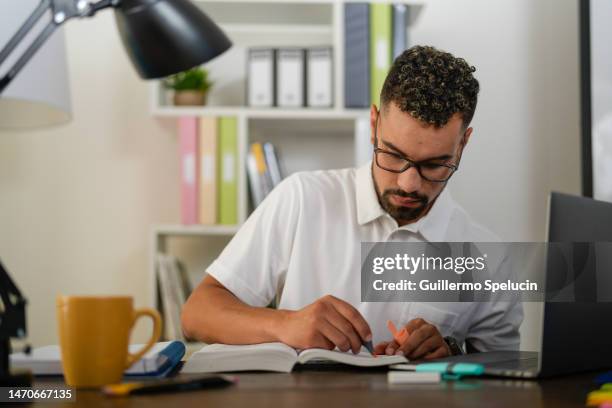 young man, highlighting a book, sitting behind his desk - reading glasses isolated stock pictures, royalty-free photos & images