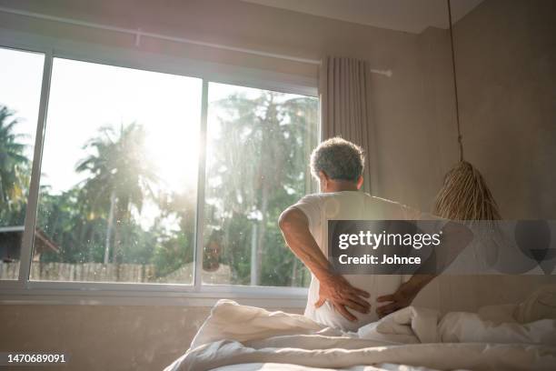 senior man struggles with backache - stijf stockfoto's en -beelden