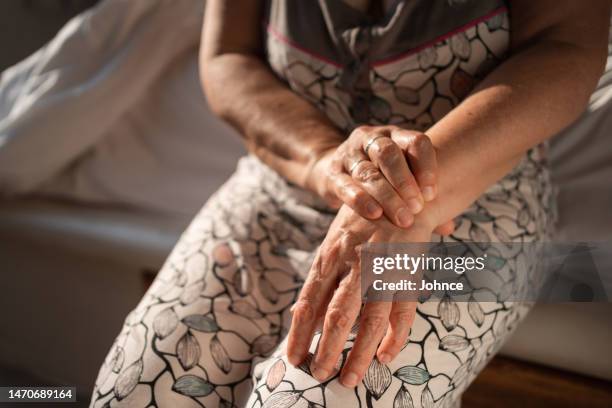 une femme âgée essaie l’auto-massage pour soulager la douleur au poignet - arthritis hands photos et images de collection