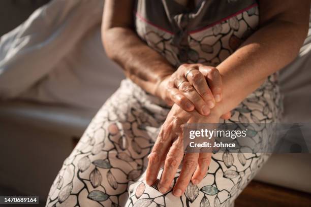 senior woman tries self-massage to relieve the wrist pain - rheumatism stock pictures, royalty-free photos & images