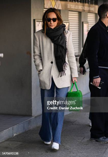 Guest is seen wearing a cream jacket, blue jeans, white shoes, green bag and black fringe scarf outside the Dries Van Noten show during Paris Fashion...