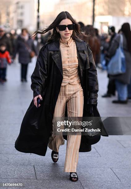 Guest is seen wearing a black leather coat, yellow Dries Van Noten top and pants and black sunglasses outside the Dries Van Noten show during Paris...
