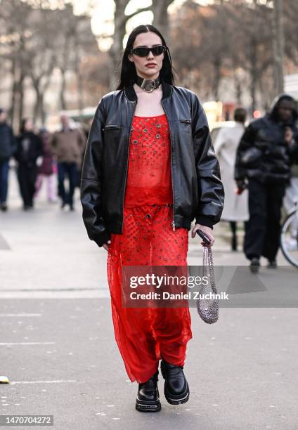 Guest is seen wearing a black jacket, red sheer dress and silver bag, black sunglasses and black and silver choker outside the Paco Rabanne show...