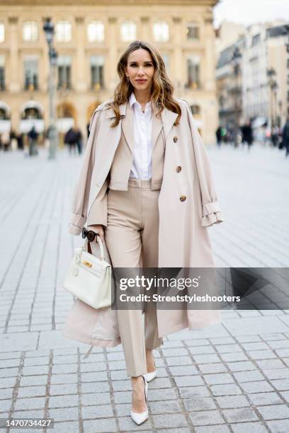 Alexandra Lapp is seen wearing COMMA trench coat in beige, COMMA short jacket in beige, COMMA blouse in white, COMMA pants in beige, HERMES Kelly bag...