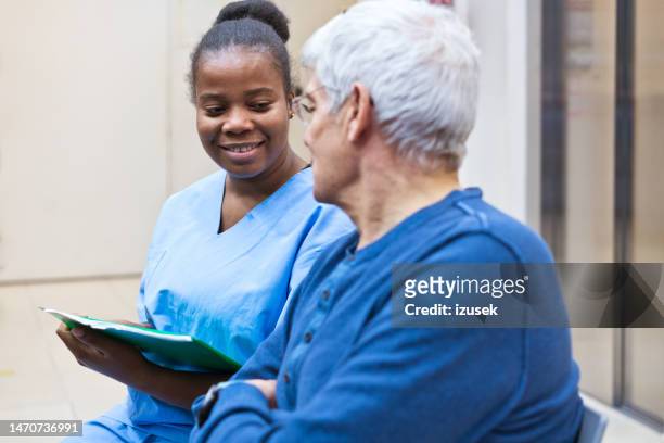nurse talking with senior man - hospice stock pictures, royalty-free photos & images