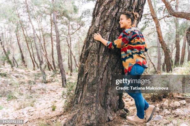 a woman hugs a huge tree. the concept of unity with nature. - big hug stock pictures, royalty-free photos & images
