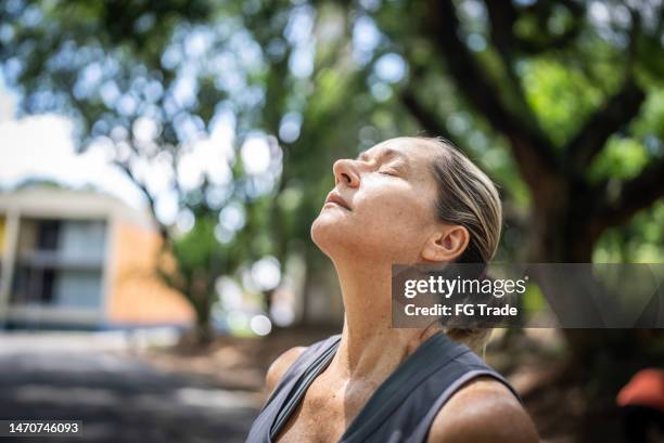 mature woman doing breathing exercise in the park - exhaling stock pictures, royalty-free photos & images