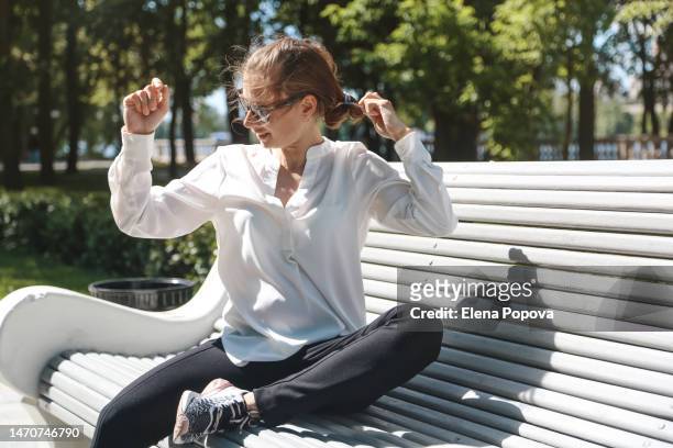 young adult pregnant woman in sunglasses relaxing at the park bench on sunny summer day - satin shirt stock pictures, royalty-free photos & images