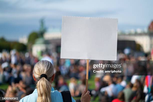 donna della vista posteriore che tiene il segno vuoto bianco con plcae per il testo alla dimostrazione pacifica del cambiamento climatico - politica e governo foto e immagini stock