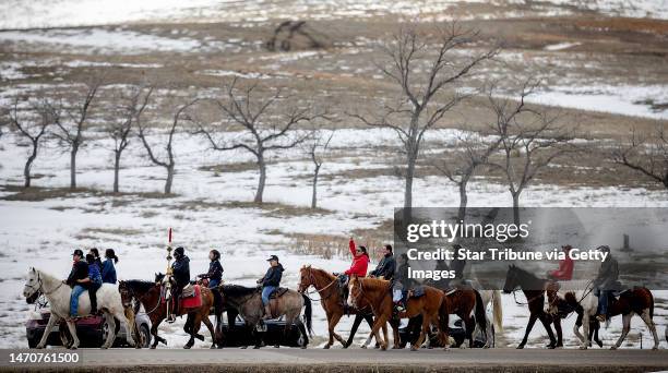Riders on horses make their way to merge with others who made a 7-mile trek to merge and meet at the Wounded Knee Memorial site, in Wounded Knee,...