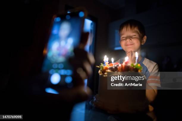 father taking photo of his little boy's birthday with cake and candles using smartphone - cake face bildbanksfoton och bilder