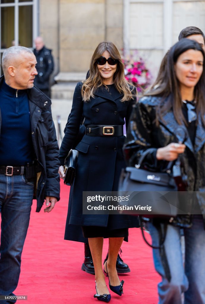 carla-bruni-wears-navy-belted-double-breasted-coat-bag-at-maison-de-lam%C3%A9rique-latine-on-march.jpg