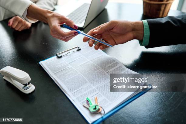 real estate agent giving a pen to the client to sign a contract for financial loan - lending stockfoto's en -beelden