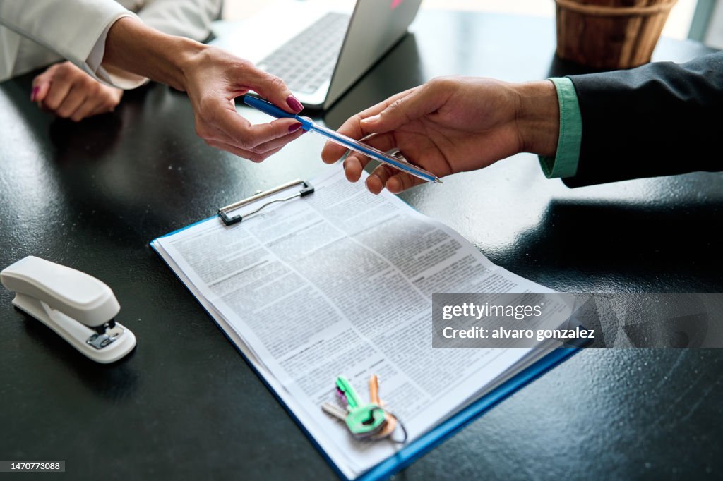 Real estate agent giving a pen to the client to sign a contract for financial loan