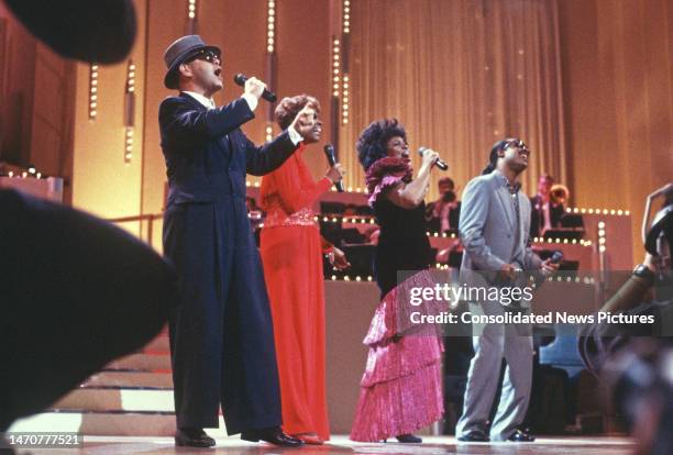 View of, from left, Elton John, Dionne Warwick, Gladys Knight, and Stevie Wonder as they perform onstage during 'AIDS Concert '88' at the John F...