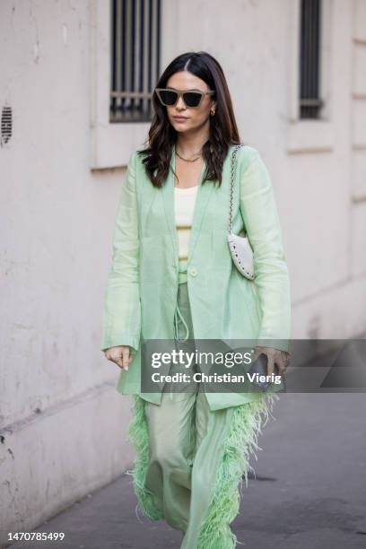 April Hennig wears light green trousers and blazer, sunglasses at Maison de l’Amérique latine on March 02, 2023 in Paris, France.