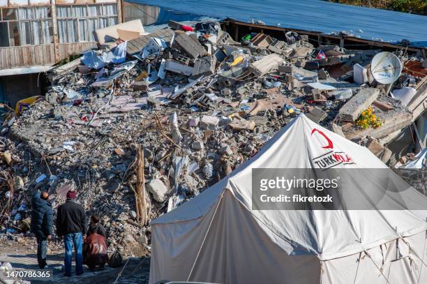 red crescent tent set up near an earthquake survivor's wrecked building - refugee camp tents stock pictures, royalty-free photos & images