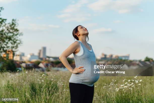 young asian pregnant woman breathing fresh air against blue sky - stretching home stock pictures, royalty-free photos & images