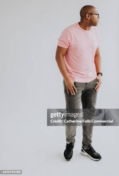 full length portrait of a casually dressed black man against a plain white backdrop. - man looking away stock pictures, royalty-free photos & images